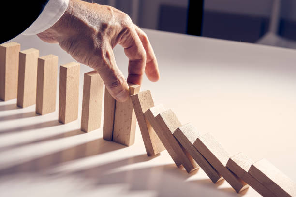 istock Men's hand risk management, falling domino blocks 1224516545