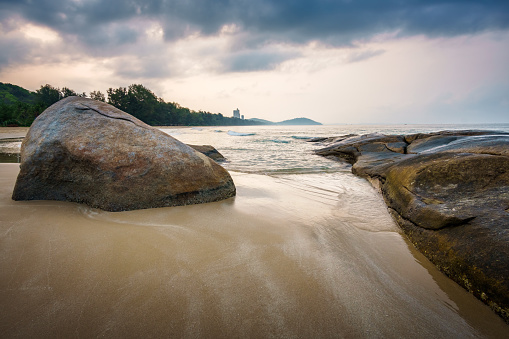 The view to the sea and nice sunrise with interesting sky is opened from the coast with rocks. Beautiful summer landscape