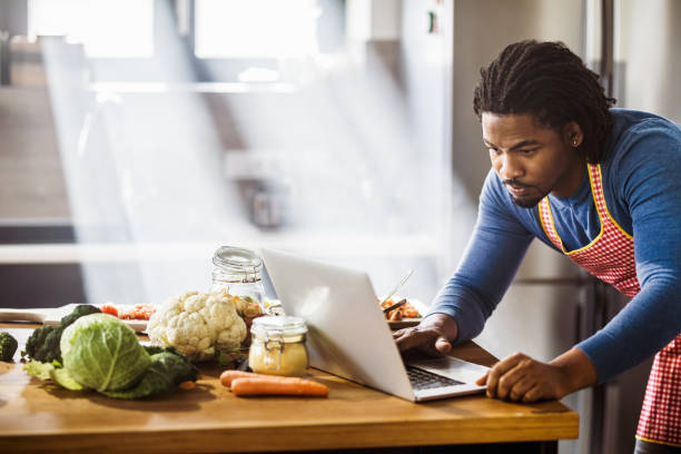 istock African American bachelor searching recipes over Internet in the kitchen. 1224519816