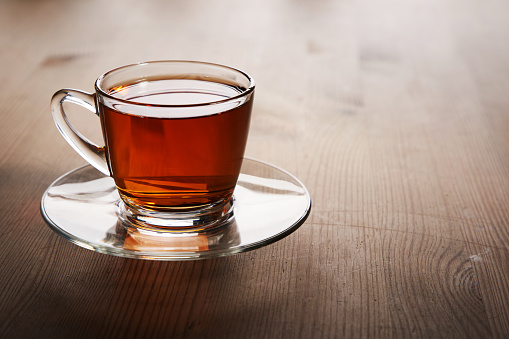 Glass cup of hot ginger tea on the black desk.