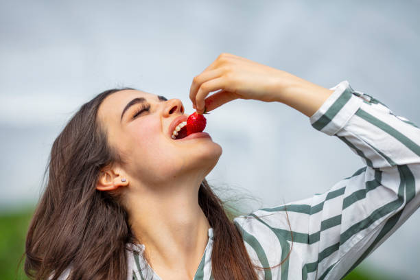 istock Pretty young female eating fresh strawberry. 1224521149