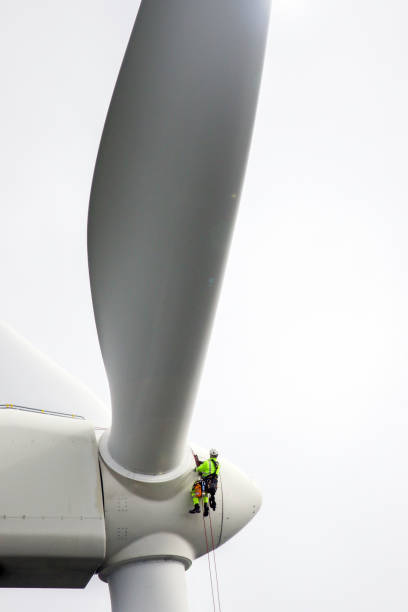 istock Professional rope access technicians rappelling down to working on blade of wind turbine and preparing rope protectors on the rope. 1224521961