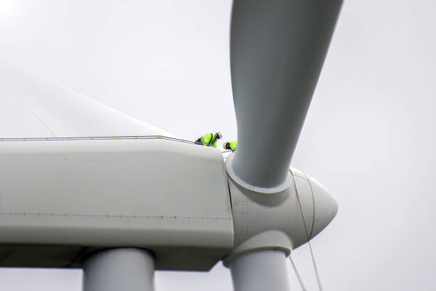 istock Two rope access technicians preparing for work on blade on hub-roof of wind turbine. 1224521966