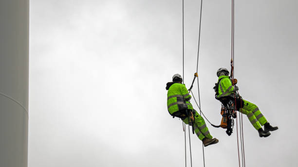 Two rope access technicians rappelling down from blade of wind turbine and they are high up stock photo