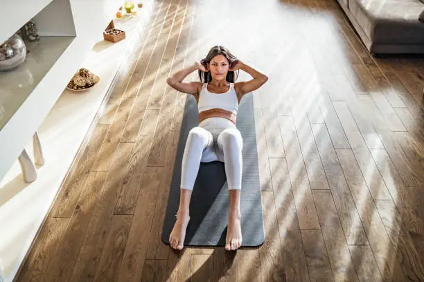 Photo of Above view of athletic woman exercising sit-ups on exercise mat.