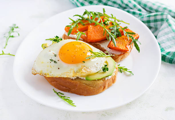 istock Healthy breakfast. Sandwich with avocado and fried egg, sandwich with fried sliced pumpkin  for healthy breakfast or snack. 1224523524