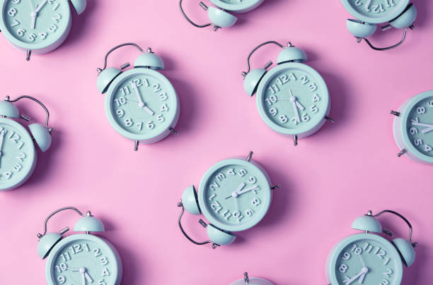Creative layout of blue alarm clock's on pastel pink background. Minimal concept