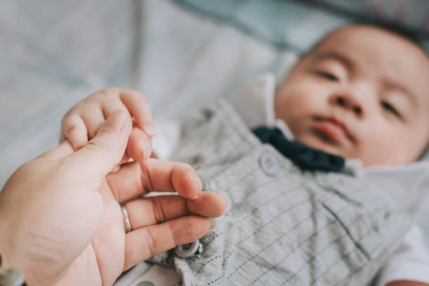 istock personal prespective first person view holding baby boy 's hand who is lying down on bed looking 1224524366