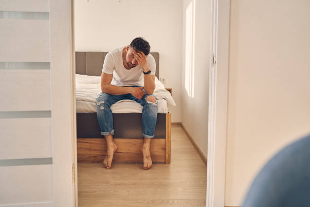 istock Sad male sitting on this bed with his head on his hand 1224527146