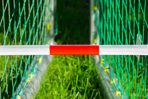 Red and white barrier tape in front of two soccer goals, concept of soccer or football fields closed to corona pandmic