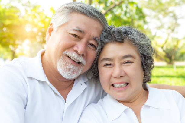 美しいカップルが抱き合う肖像画をクローズアップし、幸せな笑顔で春の公園でポーズをとります。おじいさんと祖母がリラックス。魅力的な高齢の妻と夫は健康です。医療 - senior adult couple care spring ストックフォトと画像