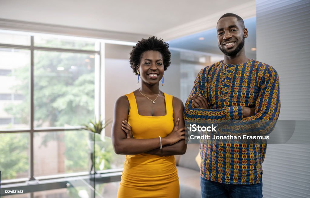Two confident young African businesspeople standing in a modern Portrait of a two smiling young African businesspeople standing confidently with their arms crossed in a modern office African Ethnicity Stock Photo