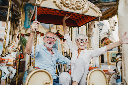 A senior couple is riding on a carousel on a summer afternoon