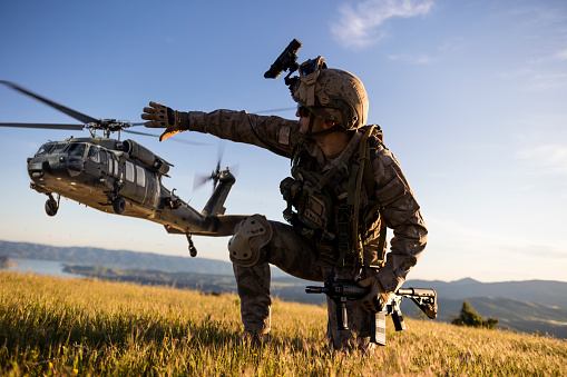 Helicóptero militar acercándose detrás del soldado del ejército arrodillado photo