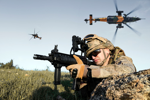 Fully armed British soldier in a fight in forest trench. About 25 years old Caucasian male.