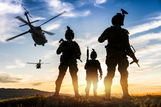 Silhouettes of soldiers during Military Mission at sunset Squad of Three Fully Equipped and Armed Soldiers Standing on Hill  at sunset us military photos stock pictures, royalty-free photos & images