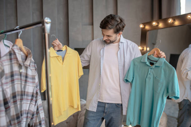 istock Man holding in his hands two tshirts on trempels 1224537385