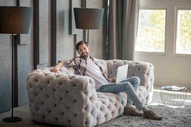 istock Man with laptop on the sofa in a cozy room 1224537428