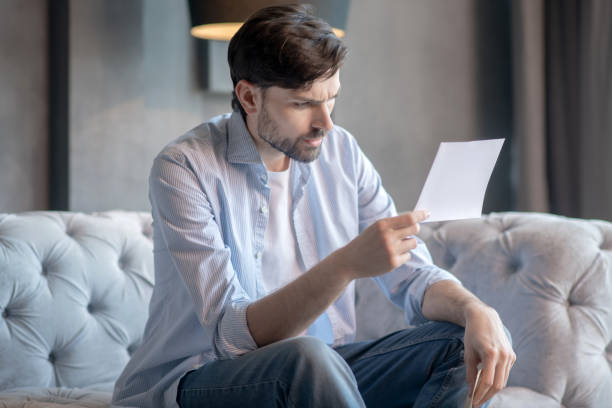 istock Attentive man frowning eyebrows with document in his hands. 1224537501