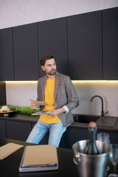 istock Young bearded man holding an envelope in his hand and looking thoughtful 1224537506