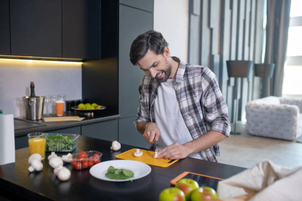 istock Smiling man slicing mushrooms on a cutting board. 1224537553