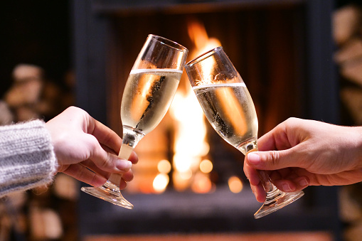 Close-up of a couple in love toasting in front of the fireplace at home