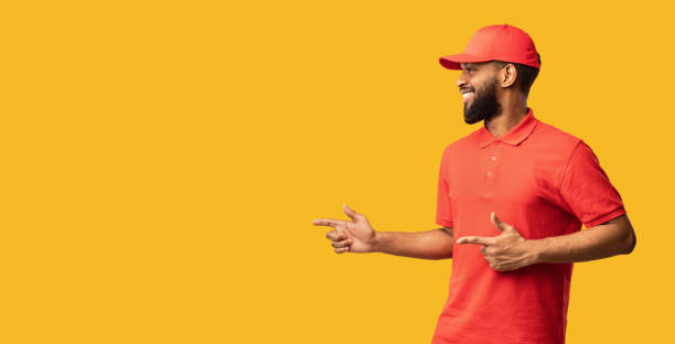 istock African Courier Pointing Fingers Aside Recommending Delivery Service, Yellow Background 1224539667