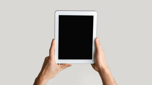 istock Closeup of young man holding tablet computer with empty screen on light background. Mockup for design. Panorama 1224539733
