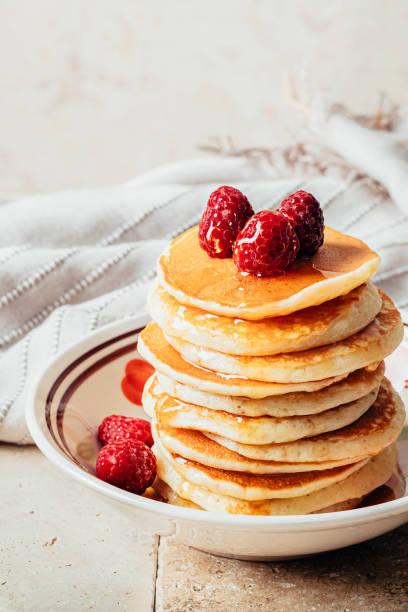 istock Pancakes poured with honey decorated with raspberries on a plate on a beige background. Copy space 1224539945