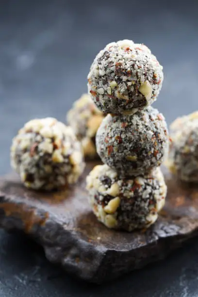 Healthy vegan snack. Homemade energy balls with hazelnuts in pile on dark stone on black background copy space vertical