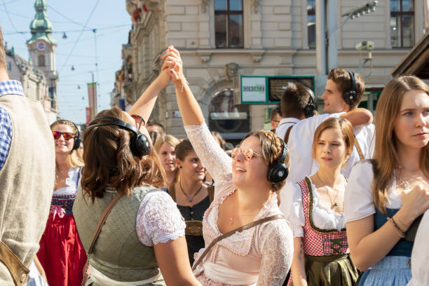 Two funny beautiful young women in bright national costumes dance on the street Graz/Austria - Sep. 2019: annual autumn festival of Styrian folk culture (Aufsteirern). Two funny beautiful young women in bright national costumes dance on the street during traditional festival. dirndl traditional clothing austria traditional culture stock pictures, royalty-free photos & images