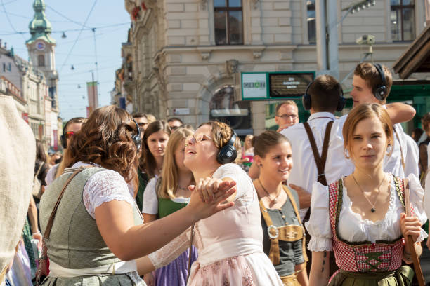 Two funny beautiful young women in bright national costumes dance on the street Graz/Austria - Sep. 2019: annual autumn festival of Styrian folk culture (Aufsteirern). Two funny beautiful young women in bright national costumes dance on the street during traditional festival. dirndl traditional clothing austria traditional culture stock pictures, royalty-free photos & images