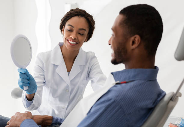 istock Pretty black dentist holding mirror for male patient 1224540813
