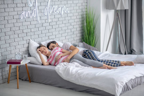 istock Dark-haired bearded man hugging his pregnant wife while sleeping 1224542830