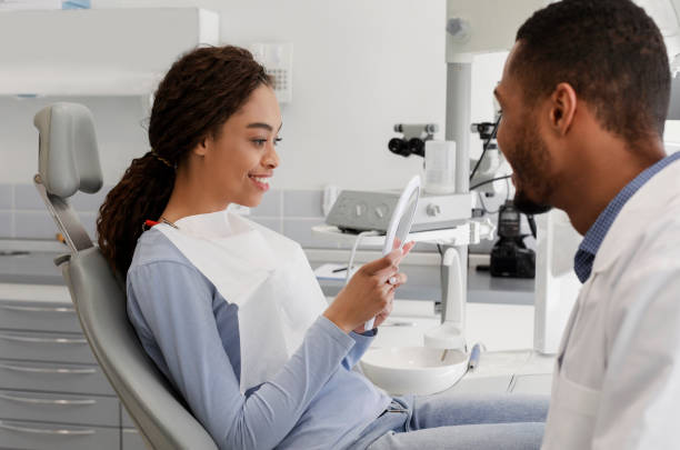 istock Satisfied african lady checking her new smile in mirror 1224545660