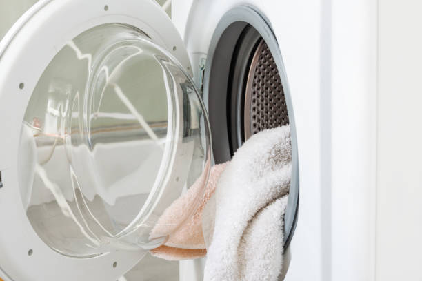 White washing machine with clean towels in a drum. Household.