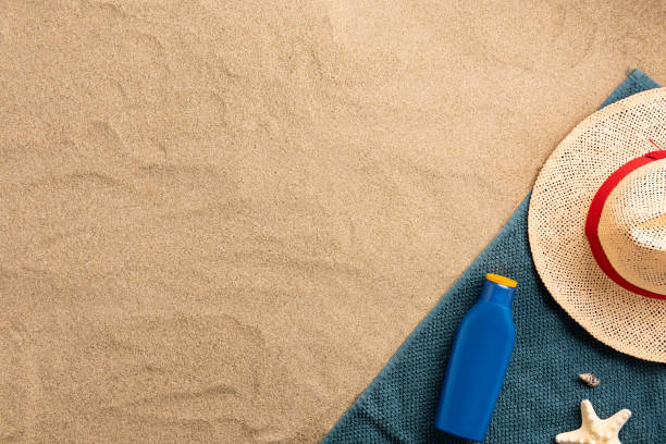 Top view of sandy beach with towel frame and summer accessories. Background with copy space and visible sand texture. Border composition made of towel stock photo