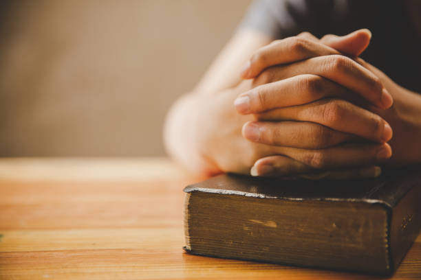 istock Praying hands of man and old bible 1224549758