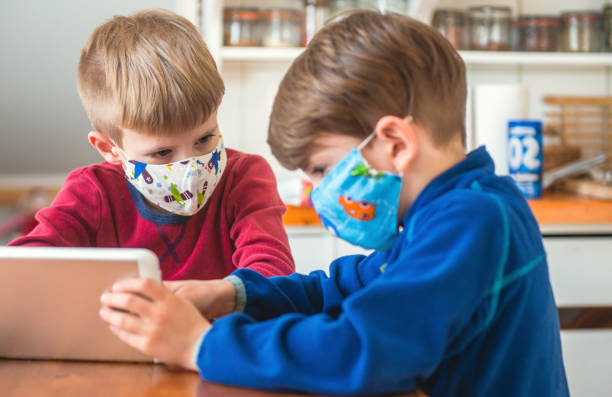 istock Boys Playing With Digital Tablet And Wearing Protective Face Mask 1224556363
