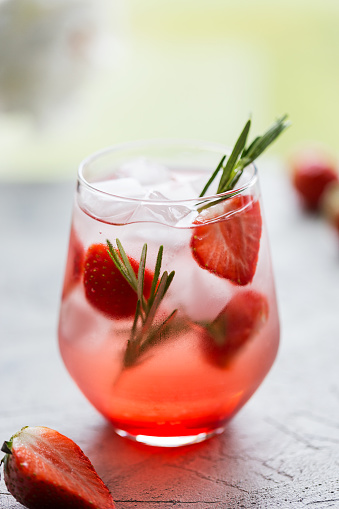Cold drink with strawberry, rosemary and ice in sunny day. Concept of freshness beverage