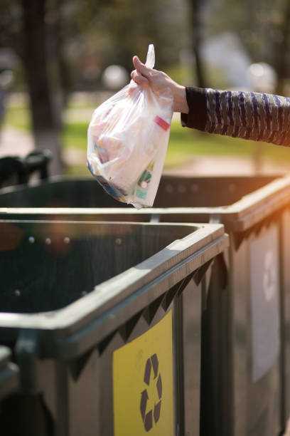 istock Hand with a bag of plastic garbage over containers for separation and sorting in Russia with the words: Glass, plastic, household waste. 1224560493