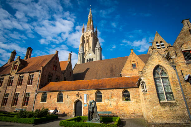 Exterior view of the old Hospital of Saint John in Bruges, whose origin dates back to the 12th century. In this religious site, the monks cared for the poor and sick pilgrims and currently houses an important museum of art and history of the city. In the background, the tower of the Church of Our Lady, another of the main monuments of Bruges.