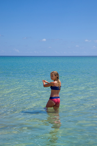 Young blond hair girl about to dive in the turquoise sea in Porto Santo beach