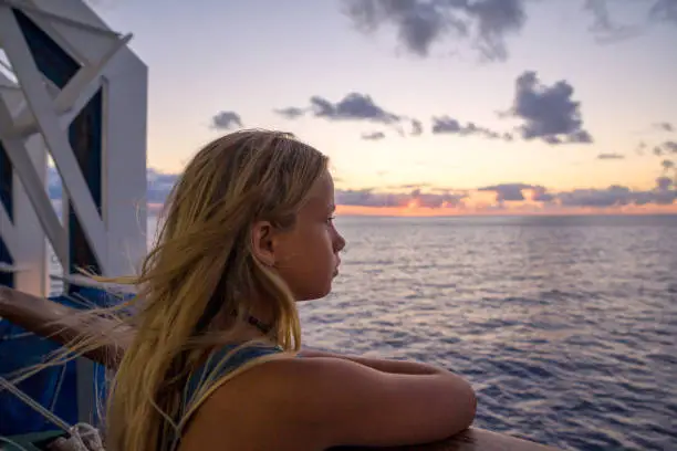 Young blond hair girl looking at the sunset from the ferry in the Atlantic Ocean