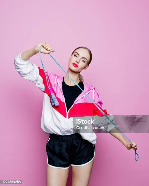 80s Style Portrait Of Confident Woman In Sports Clothing Against Pink Background Stock Photo - Download Image Now