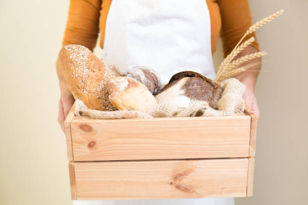 istock Baker holding wooden box with freshly baked bread 1224564517
