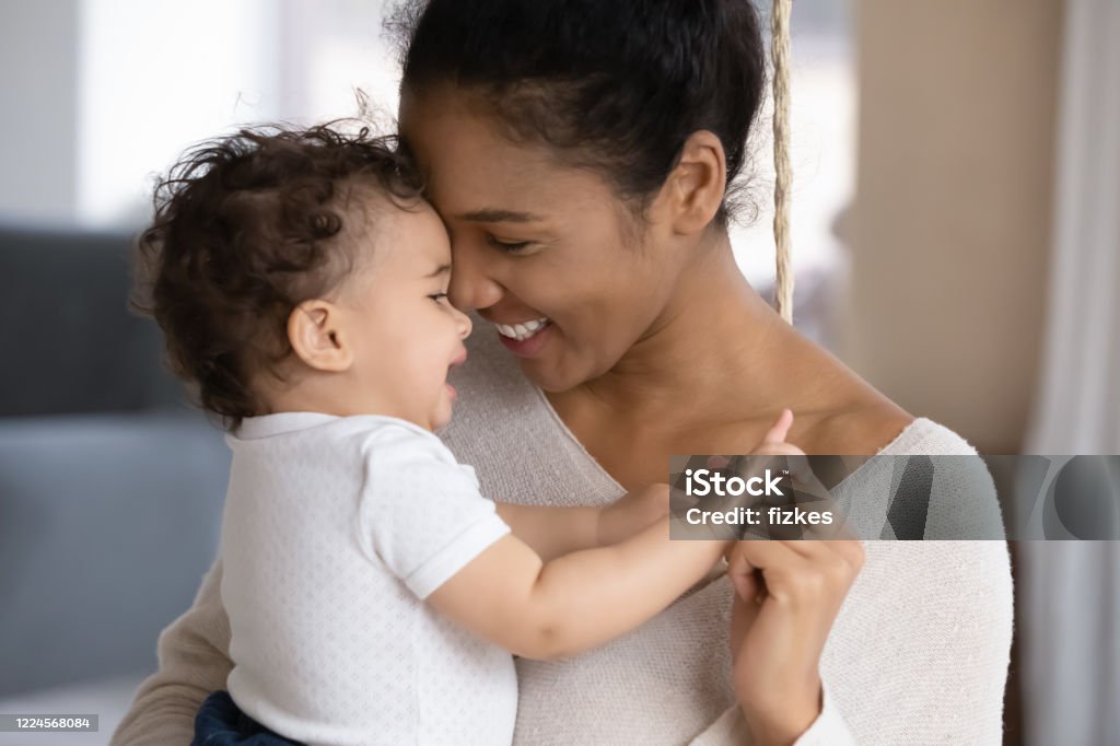 Loving biracial mom hug cute little baby child Close up of happy young african American mother hug cuddle little infant or toddler, loving smiling biracial mom embrace small baby child, enjoy tender family moment, motherhood, childcare concept Mother Stock Photo