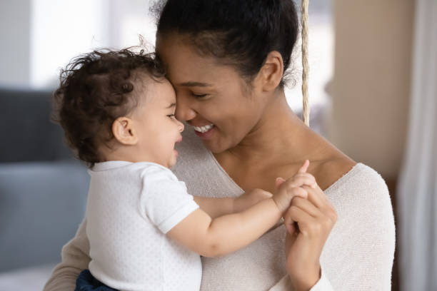 kochająca dwurasowa mama przytula urocze małe dziecko - baby zdjęcia i obrazy z banku zdjęć