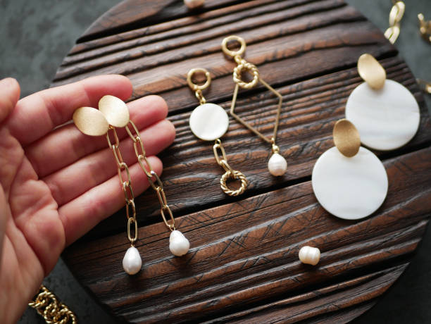 gold jewelry in hand on a flat lay - necklace jewelry bead homemade imagens e fotografias de stock
