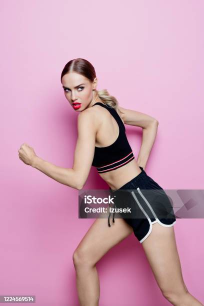 Portrait Of Running Woman In Sports Clothing Against Pink Background Stock Photo - Download Image Now